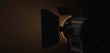 Profesyonel stüdyo ışıkları karanlıkta kullanmak için. Metal vücudun bir kısmını aydınlatan yumuşak, sıcak bir ışık yayıyor. Sahne arkasında ışıklandırma ekipmanları.