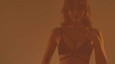 Dantelli iç çamaşırlı bir kadının sanatsal silueti, dramatik bir etki yaratmak için sıcak, karamsar ışıklandırmayla yakalanmış..