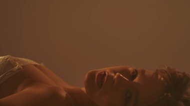 Yumuşak, ılık bir ışıkla yıkanmış, cilt dokusunu ve dingin ifadesini vurgulayan bir kadın profiline yakın plan..