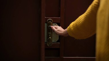 Tahta kapıyı açmak için pirinç kapı kolunu çeviren birinin yakın plan fotoğrafı. Eline odaklanarak..