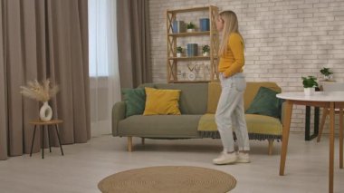 Genç bir kadın endişeli bir ifadeyle oturma odasında volta atıyor, endişeyle birini bekliyor..