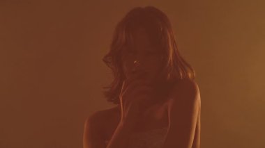 Dantelli iç çamaşırlı bir kadının sanatsal silueti, dramatik bir etki yaratmak için sıcak, karamsar ışıklandırmayla yakalanmış..