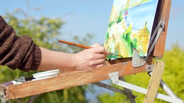 Bir sanatçının el resmi açık havada bir tuval üzerinde canlı gökyüzü ile bir manzara..
