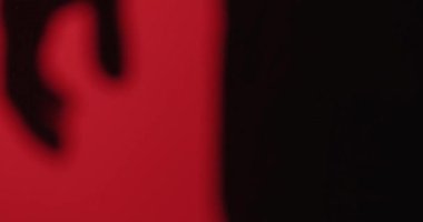 Bir elin koyu gölgesi bir yumruğa yapışmış kırmızı bir arka plan, minimalist, gizemli, soyut bir konsept..