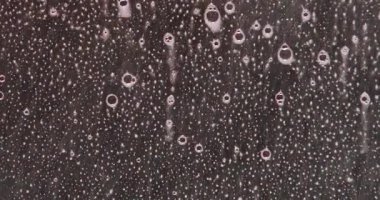 Köpük sıvısını cama püskürtüyor. Köpük kabarcıkları cam yüzeyden aşağı doğru akar ve siyah arka planda soyut bir doku oluşturur. Görsel efektler ve arka plan değişimi için ideal. Yavaş çekim.