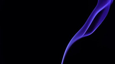 Narin bir mavi duman zerafetle siyah bir arka plana doğru kıvrılır ve bir gizem hissi yaratır. Yavaş çekim