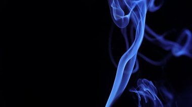 Narin mavi dumanların büyüleyici bir görüntüsü. Karanlık bir arkaplanda zarafetle kıvrılıyor. Yavaş çekim