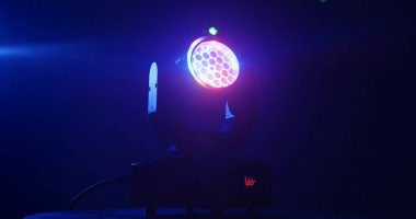 Canlı bir sahne ışığı, çarpıcı bir parıltıyla karanlık bir çevreyi aydınlatan renkli bir ışık yayar..