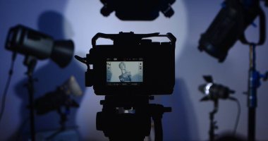 Fotoğraf stüdyosundaki bir kameranın silueti. Işıklandırma ekipmanlarıyla. Ekranda bir manken var. Profesyonel ışıklandırma ekipmanıyla sahne arkası fotoğraf çekimi.