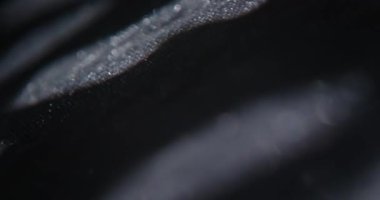 Soyut ışık noktalarının yakın çekimleri koyu dokulu yüzeylere yansıtılarak modern arkaplanlar için yüksek kontrastlı organik desenler oluşturulmuştur. Yavaş çekim.