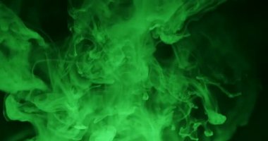 Göksel yeşil duman, karanlık bir arkaplanda zarif bir şekilde kıvrılarak gizemli ve atmosferik bir manzara yaratır. Yavaş çekim.