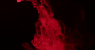 Ölümcül kırmızı duman, karanlık bir arkaplanda zarif bir şekilde kıvrılarak gizemli ve atmosferik bir manzara yaratır. Yavaş çekim.