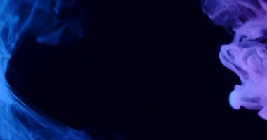 Göksel mavi duman, karanlık bir arkaplanda zarif bir şekilde kıvrılarak gizemli ve atmosferik bir manzara yaratır. Yavaş çekim.