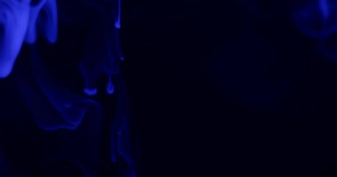 Mavi dumanlı soyut bir fotoğraf karanlık bir arka plana doğru kıvrılır ve mistik bir atmosfer yaratır..