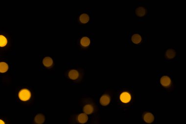 Bulanık altın bokeh ışıkları karanlık bir arkaplan karşısında soyut ve zarif bir atmosfer yaratır..