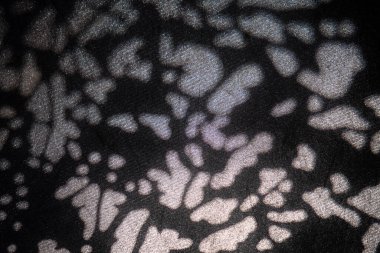 Soyut ışık noktalarının yakın çekimleri koyu dokulu yüzeylere yansıtılarak modern arkaplanlar için yüksek kontrastlı organik desenler oluşturur..