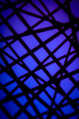 Canlı mavi ve mor ışıkta siyah geometrik gobo gölge deseni, teknoloji, tasarım, gece hayatı veya yaratıcı altyapılar için modern soyut bir doku oluşturur..