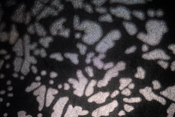 Soyut ışık noktalarının yakın çekimleri koyu dokulu yüzeylere yansıtılarak modern arkaplanlar için yüksek kontrastlı organik desenler oluşturur..