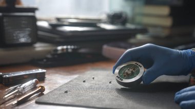 Eldivenli bir el, mekanik bir bileşen üzerinde dikkatle çalışır..