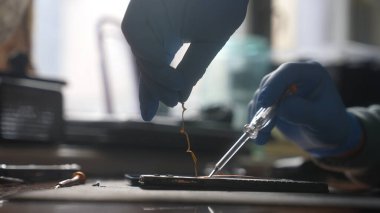Bir teknisyenin eldiven giyip dikkatli bir şekilde hassas aletlerle akıllı telefon mikroçipleri üzerinde çalışırken elektronik onarım işleminin karmaşık sürecini vurguluyor..
