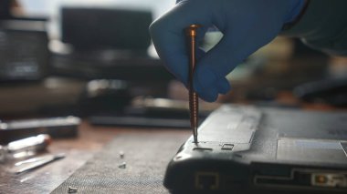 Eldiven takan bir teknisyen dizüstü bilgisayarı tamir etmek için tornavida kullanır..