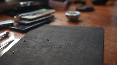 Ahşap bir masaya saçılmış, yumuşak desenli bir yüzeye odaklanmış, küçük tamir araçlarının yakın görüntüsü.