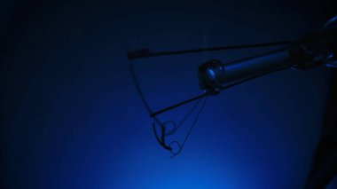 Yumuşak mavi eğimli arkaplana karşı bir ampul filamanının detaylı yakın çekimi, karmaşık tel detaylarını gösterir.