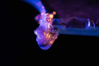 Camın üzerindeki buz kristallerinin ve buz desenlerinin renkli ışıkla aydınlatılmış makro fotoğrafı canlı bir etki yaratıyor..