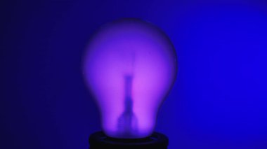 Mavi arka planda renk değiştiren sıcak, parlak bir ampul. Yeniliğin ve sıcaklığın özünü yakalar..