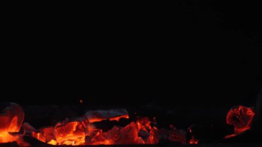 Koyu bir ızgarada parlayan kömür közlerine, turuncu ısıya ve uçan kıvılcımlara yakın durun. Barbekü, yakıt, enerji ve yüksek sıcaklık kavramları için dramatik yangın arka planı.