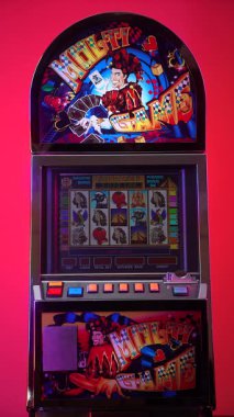 Dnipro, Ukrayna - 17 Şubat 2026: Renkli Multi Game joker tasarımlı eski kumarhane slot makinesi ve ekranda canlı kırmızı gradyan arka planına karşı duran Aztek Gold oyunu. Dikey video.