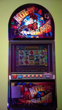 Dnipro, Ukrayna - 17 Şubat 2026: Renkli Multi Game joker tasarımlı eski kumarhane slot makinesi ve ekranda Aztec Gold oyunu, renkli renkli renkli bir arka plan karşısında duruyor. Dikey video.