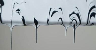 Siyah ve beyaz boyanın yumuşak gri bir arkaplana karşı camdan aşağı akması tasarım ve reklamcılık için minimalist soyut bir doku yaratıyor..