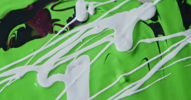 Siyah ve yeşil boyaların üzerine dökülen beyaz boyanın kapanışı, camdan aşağı akması, dinamik dalgalı çizgiler ve yaratıcı tasarım için modern bir sanat dokusu yaratması..