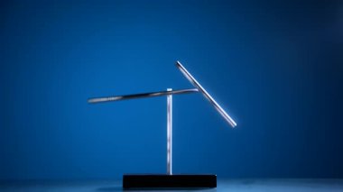 Minimalist manyetik sarkacın masa heykeli mavi arka planda dengeleniyor. Denge, hareket, fizik ve tasarım kavramları için modern kinetik nesne.