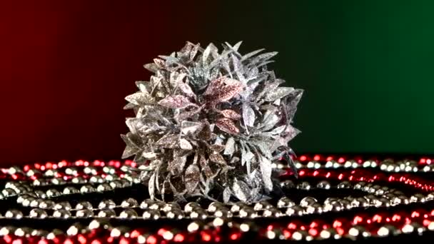 Unusual silver toy for Christmas or New Year and beads, rotation, on red and green — Stock Video