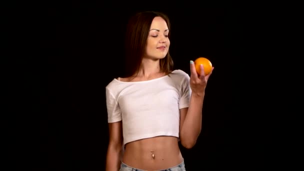Jovem, desportiva, mulher magra com uma laranja e maçã, escolha, em preto — Vídeo de Stock