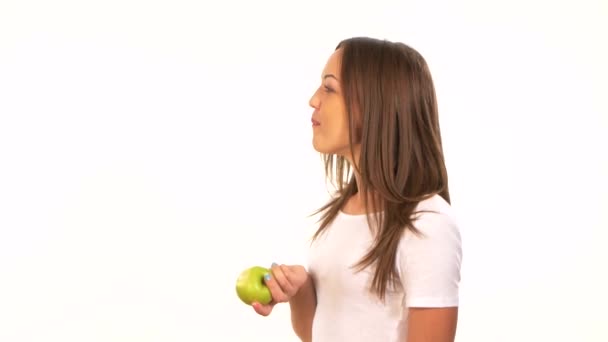 Beautiful healthy girl biting a juicy green apple, on white — Stock Video