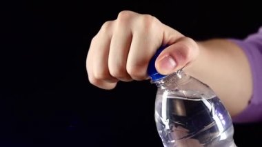 Eller yukarı ve karanlık, yavaş hareket, sıçrama, sprey, kabarcıklar üzerinde tatlı su mavi bir şişe açma