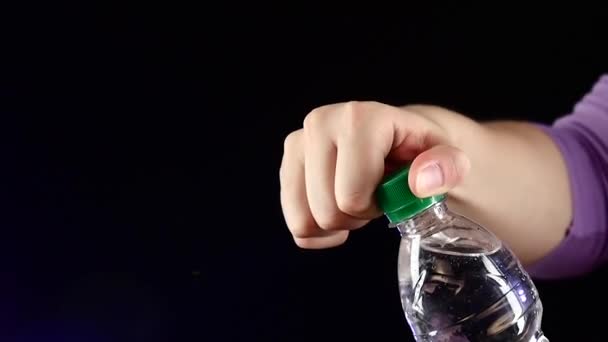 Manos arriba y abriendo una botella verde de agua dulce en cámara oscura, lenta, salpicadura, aerosol, burbujas — Vídeos de Stock