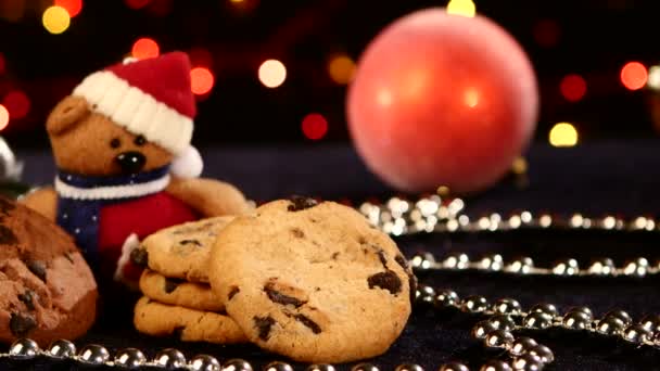 Kerstboom, cookies met decoratie, dennenappel op zwart, kralen, bokeh, licht, garland, cam oves naar links — Stockvideo