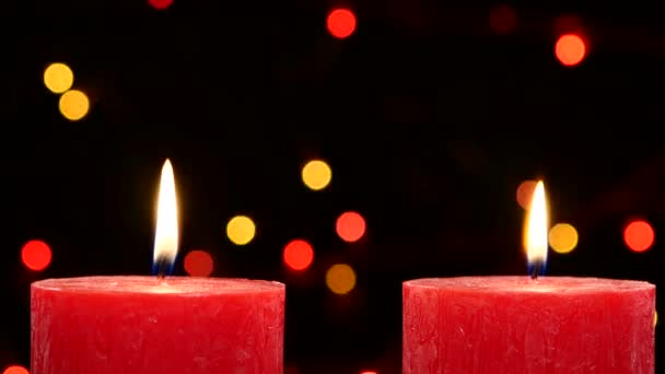 Dos velas rojas con decoraciones de Navidad en negro, bokeh, luz, guirnalda, leva se mueve de arriba hacia abajo — Vídeos de Stock