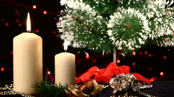 Due candele bianche con decorazioni natalizie e albero su nero, bokeh, luce, ghirlanda, rotazione — Video Stock