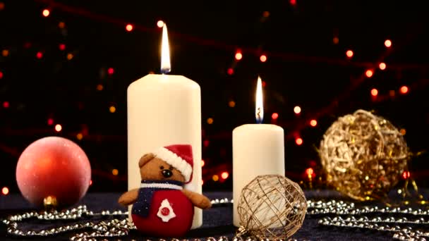 Duas grandes velas brancas com bolas e pelúcia para o Natal em preto, bokeh, luz, guirlanda, mudança dinâmica de foco — Vídeo de Stock