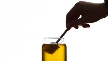 Cam Kavanoz bal ile ahşap drizzler, çöpleri hiç izole üzerinde beyaz, ağır çekim