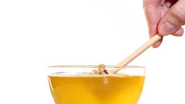 Prendere a mano il miele dalla ciotola con cucchiaio di legno dipper, su bianco, rallentatore — Video Stock