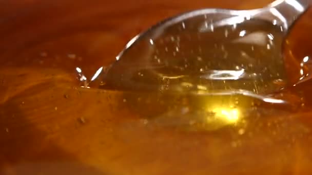 Prendre le miel par cuillère métallique dans un bol en bois, au ralenti, macro 