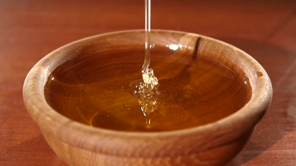 Taking honey by metal spoon in wooden bowl, flowing down, slow motion — Stock Video