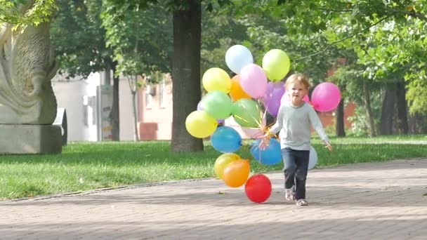 Συναισθηματικό κοριτσάκι τρέχει με πολύχρωμα μπαλόνια, αργή κίνηση — Αρχείο Βίντεο