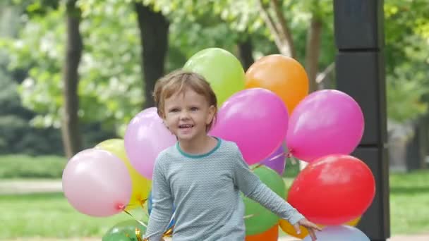 Chica emocional corre con globos multicolores, cámara lenta. De cerca. — Vídeo de stock